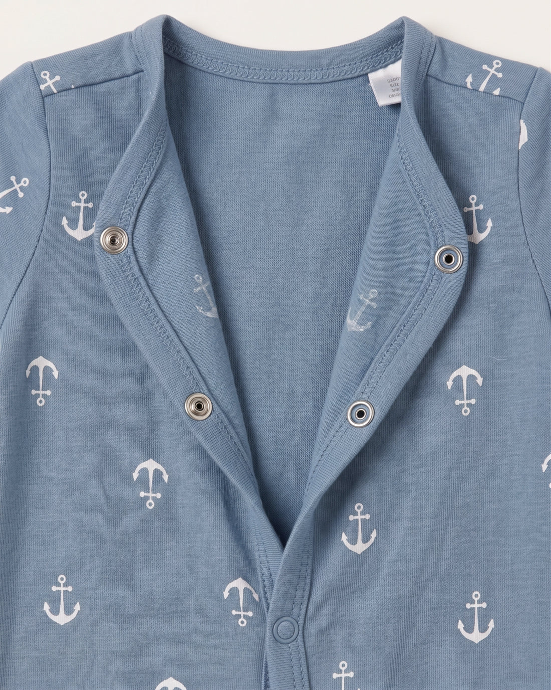 Steel blue baby jumpsuit with white nautical anchor print, short sleeves, and diagonal snap button front, flat lay on white background