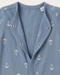 Close-up of steel blue baby jumpsuit neckline showing white anchor print pattern and silver snap button detail