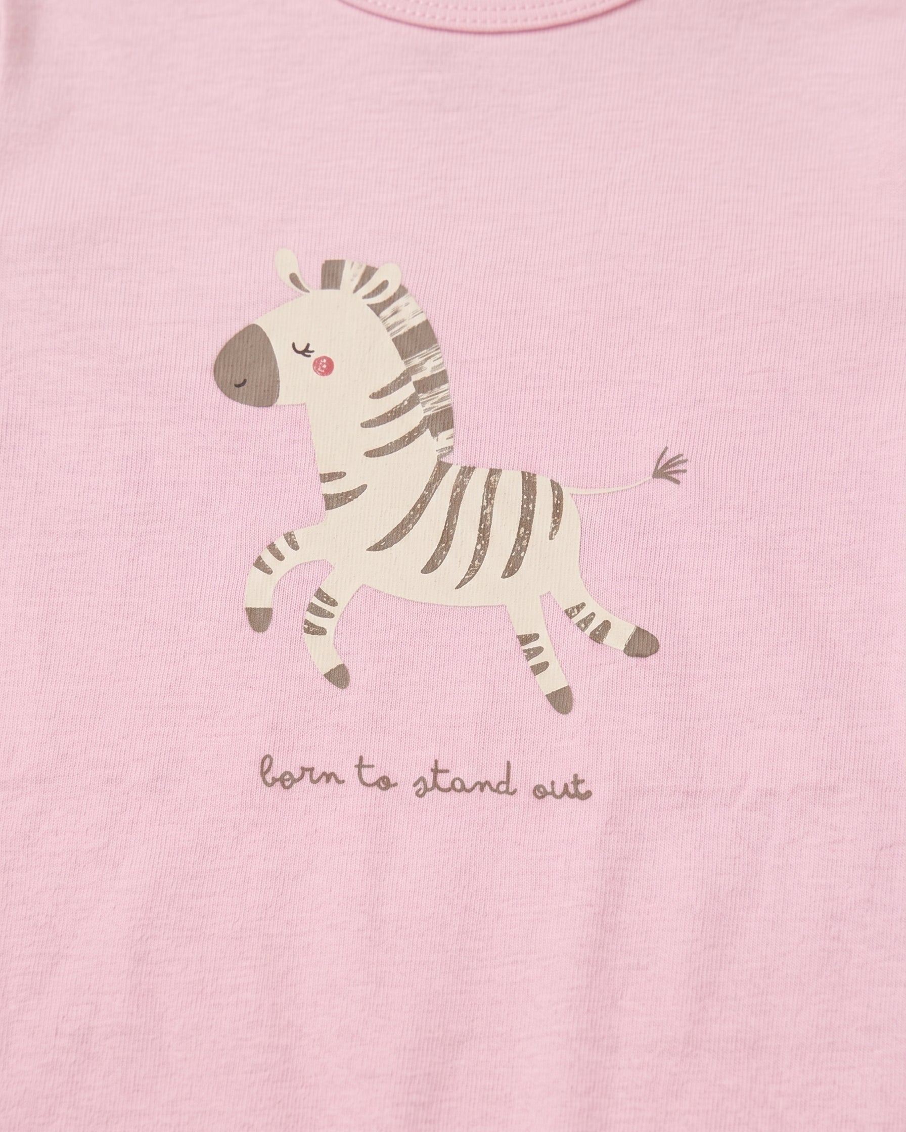 Close-up of blush pink baby romper chest area showing cute illustrated zebra print and "born to stand out" handwritten slogan on soft cotton fabric