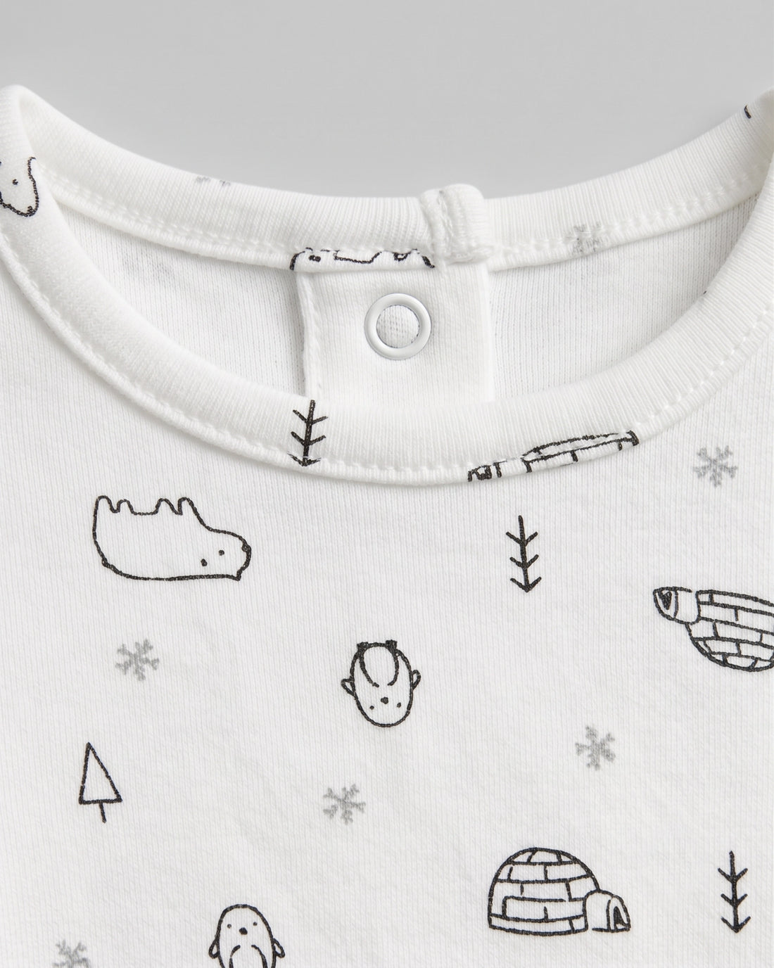 PTex Fashion off-white baby footed romper with allover arctic polar bear, penguin and igloo print, flat lay