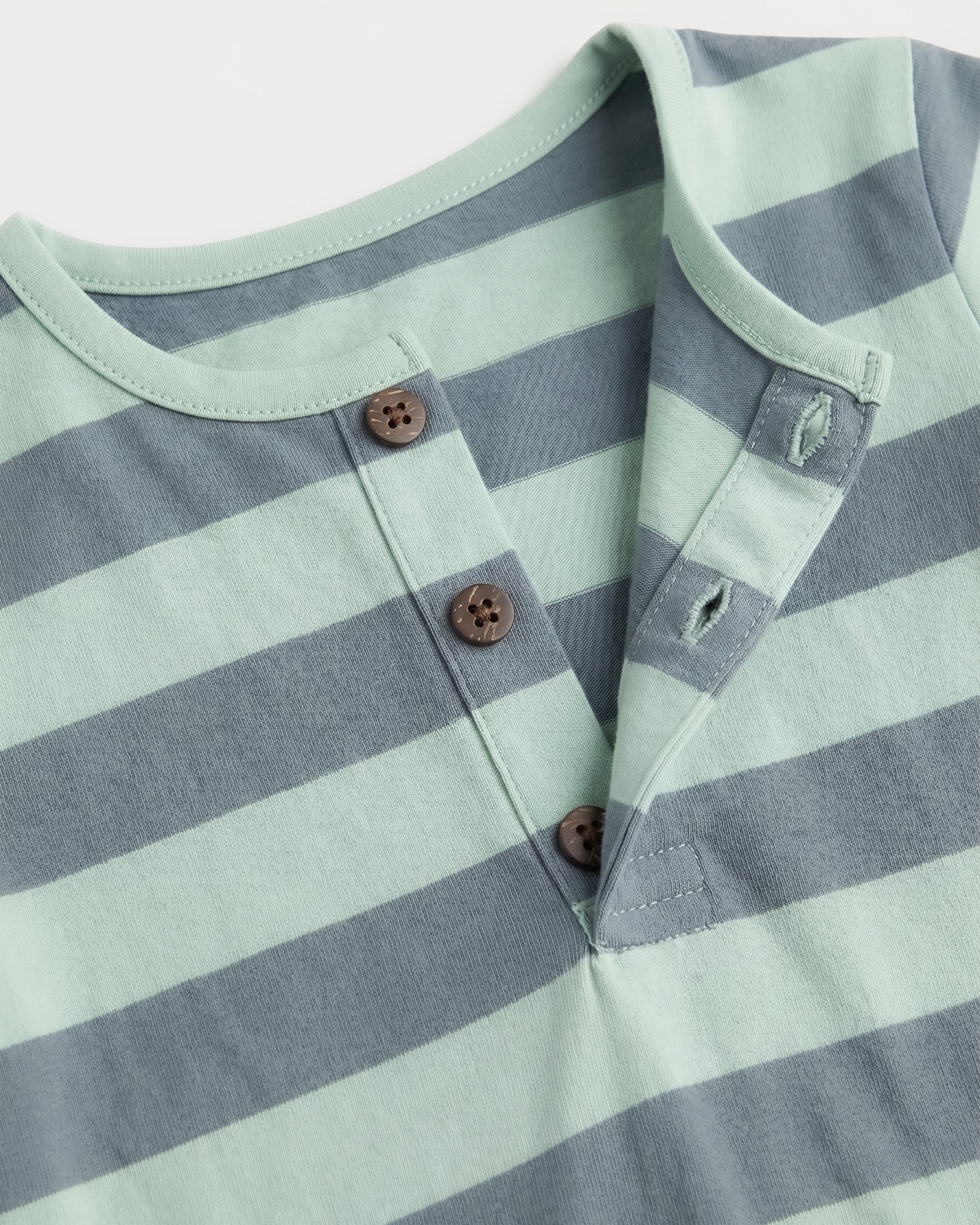 Close-up of sage green and slate blue striped baby romper neckline with three-button henley placket — PTex Fashion
