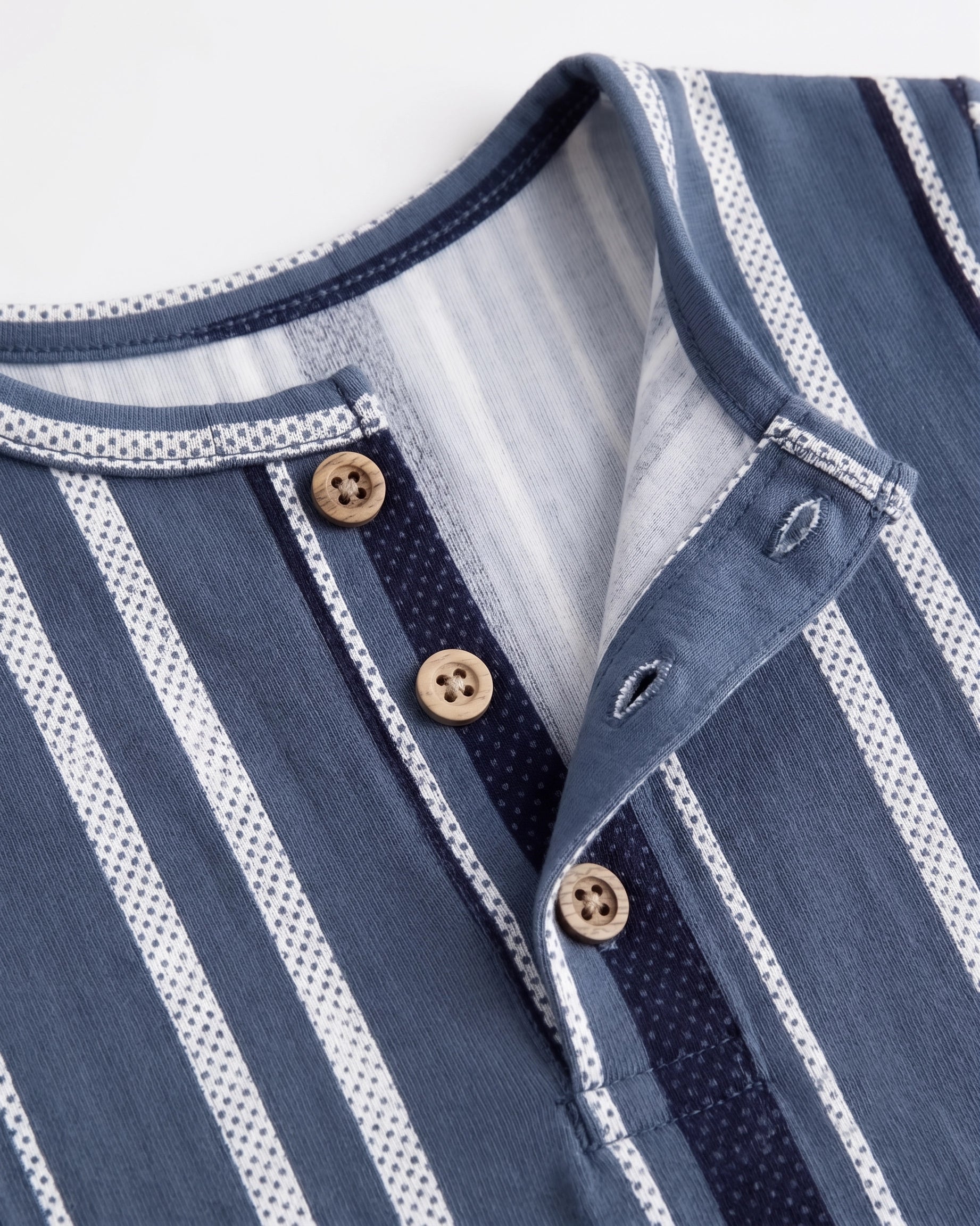 Close-up of blue striped baby romper showing wood-tone buttons and placket — PTex Fashion