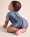 Blue striped baby romper on a wooden hanger showing button placket and leg press studs — PTex Fashion