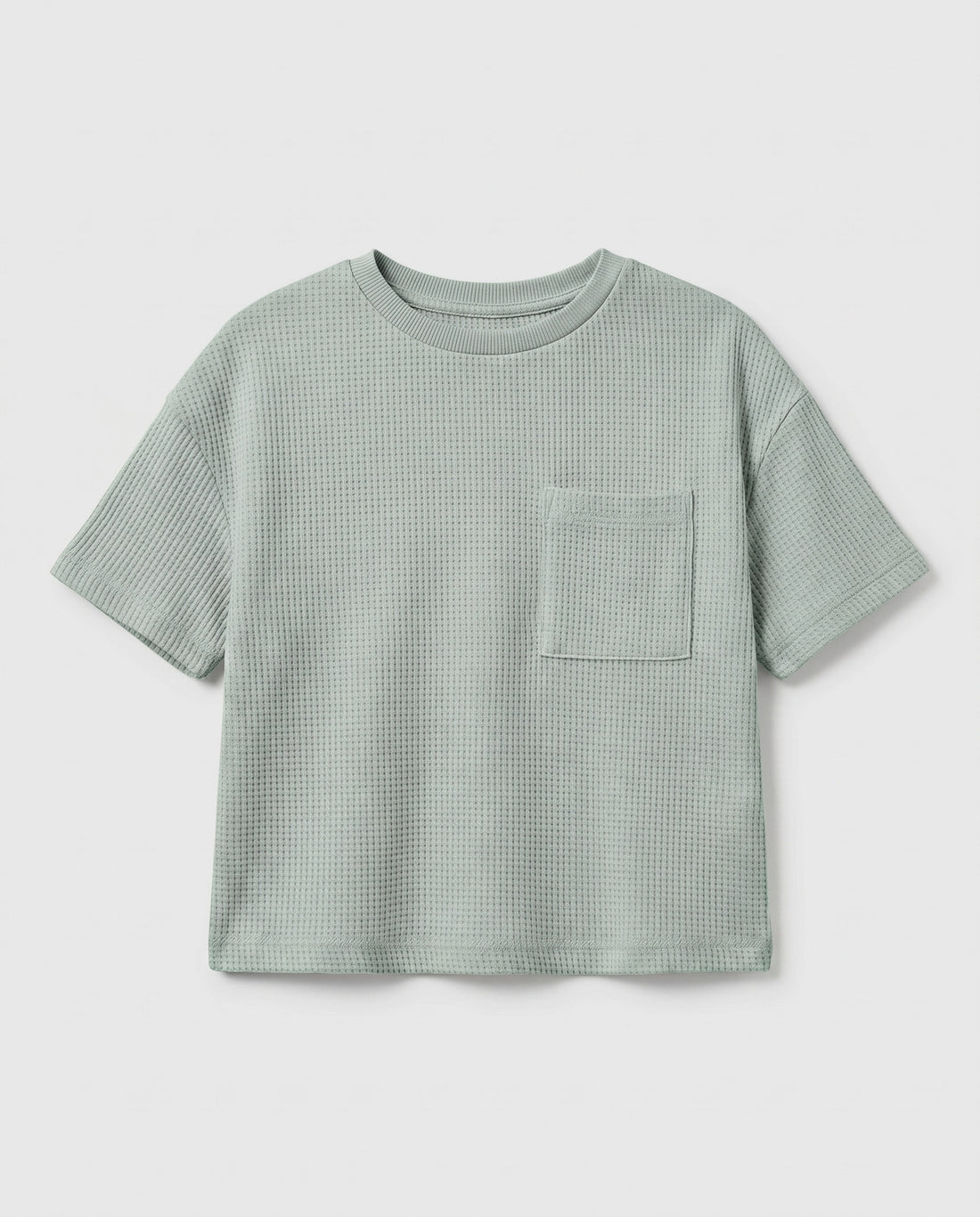 Boy's sage mint waffle cotton t-shirt with relaxed boxy fit, ribbed crewneck, and patch chest pocket, photographed flat on a soft grey backdrop.