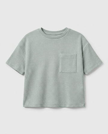 Boy's sage mint waffle cotton t-shirt with relaxed boxy fit, ribbed crewneck, and patch chest pocket, photographed flat on a soft grey backdrop.