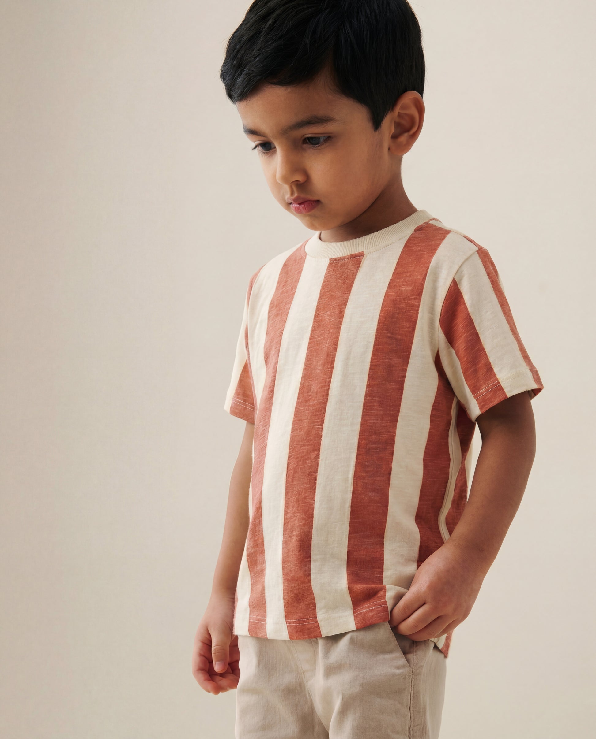 Child wearing a red and white striped shirt against a plain background
