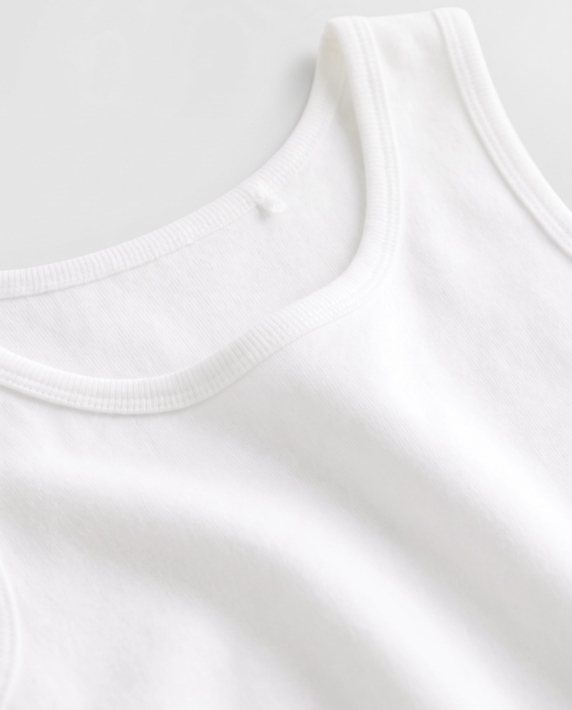Close-up of soft ribbed cotton fabric and neckline stitching on PTex Fashion boys' white school undershirt vests