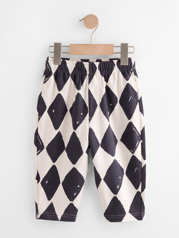 PTex Fashion harlequin print kids' trousers in charcoal and off-white, shown on a wooden hanger