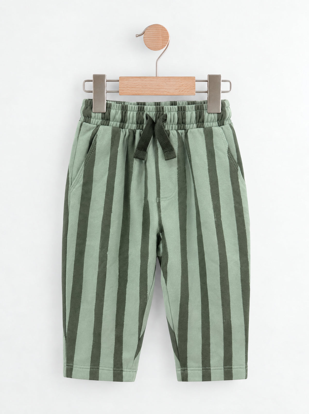PTex Fashion sage and forest green striped kids' trousers on a wooden hanger
