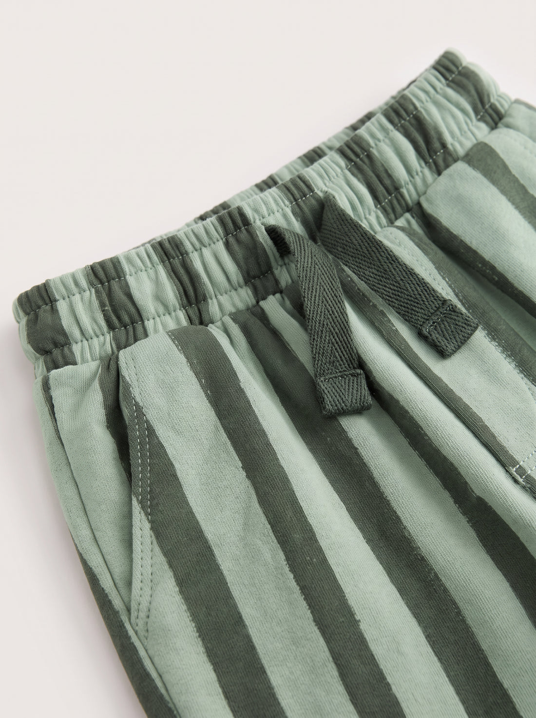 PTex Fashion sage and forest green striped kids' trousers on a wooden hanger