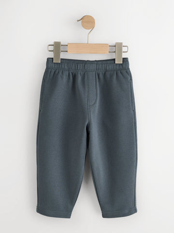 Slate blue fleece joggers with elastic waist and side pockets on a wooden hanger - PTex Fashion