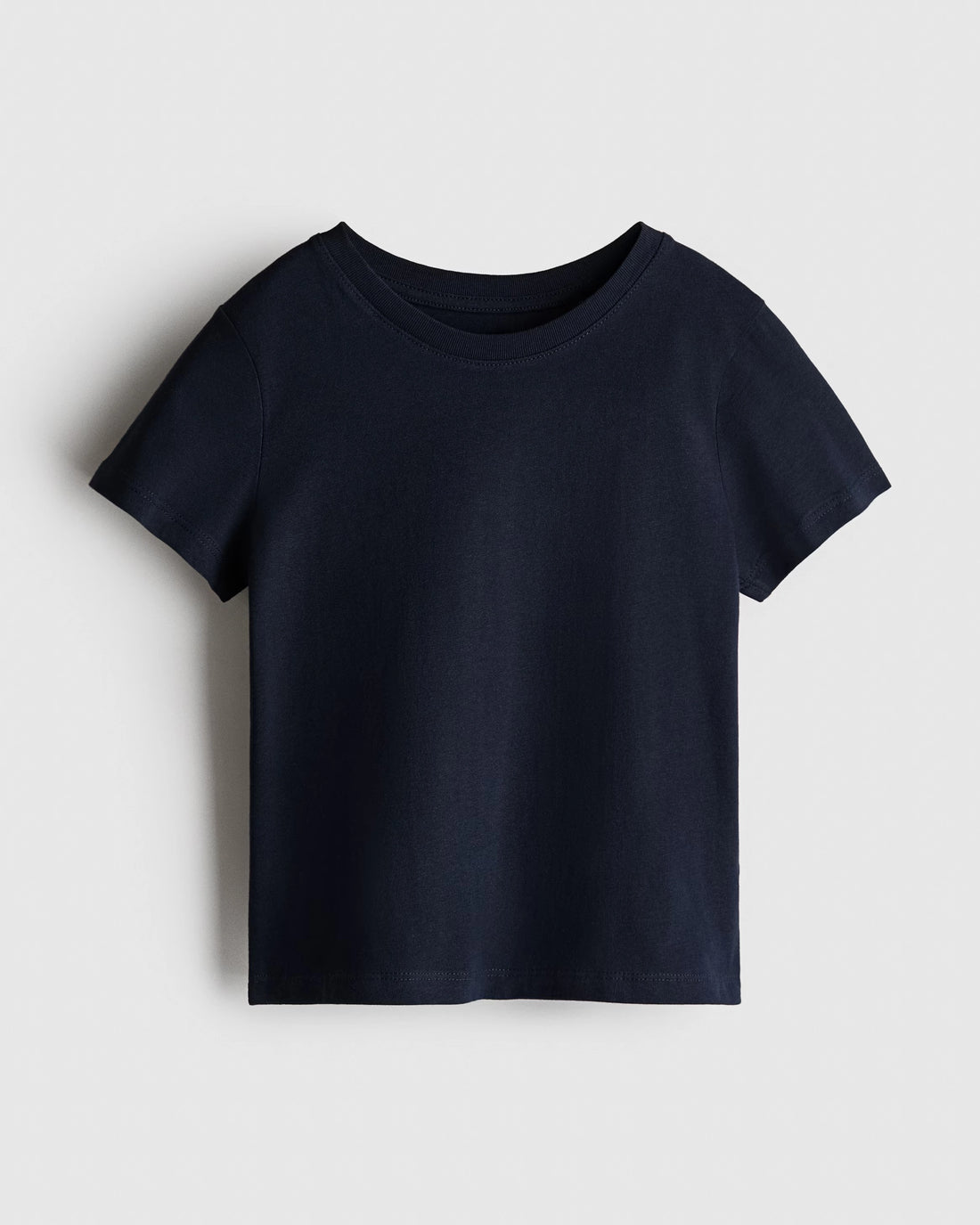 Boy's navy blue regular fit cotton t-shirt with ribbed crewneck and short sleeves, photographed flat on a soft white backdrop.