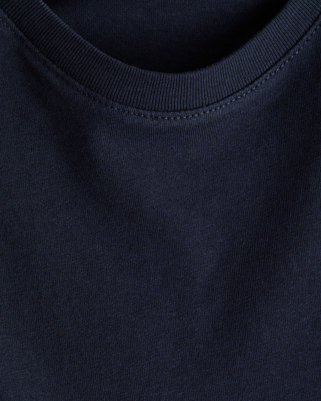 Boy's navy blue regular fit cotton t-shirt with ribbed crewneck and short sleeves, photographed flat on a soft white backdrop.