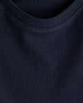 Close-up detail of a boy's navy blue cotton t-shirt showing the smooth jersey fabric and neatly stitched ribbed crewneck collar.