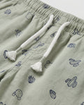 Close-up of sage green cotton twill fabric with navy cactus print, white drawstring and elastic waistband on boys' shorts
