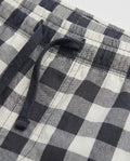 Close-up of boys' woven cotton short pant waistband showing navy drawstring and elasticated detail on navy and off-white oversized check fabric