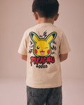 Young boy showing the back of a cream kids' t-shirt with a bold graffiti-style Pikachu winking face graphic and lightning bolt details