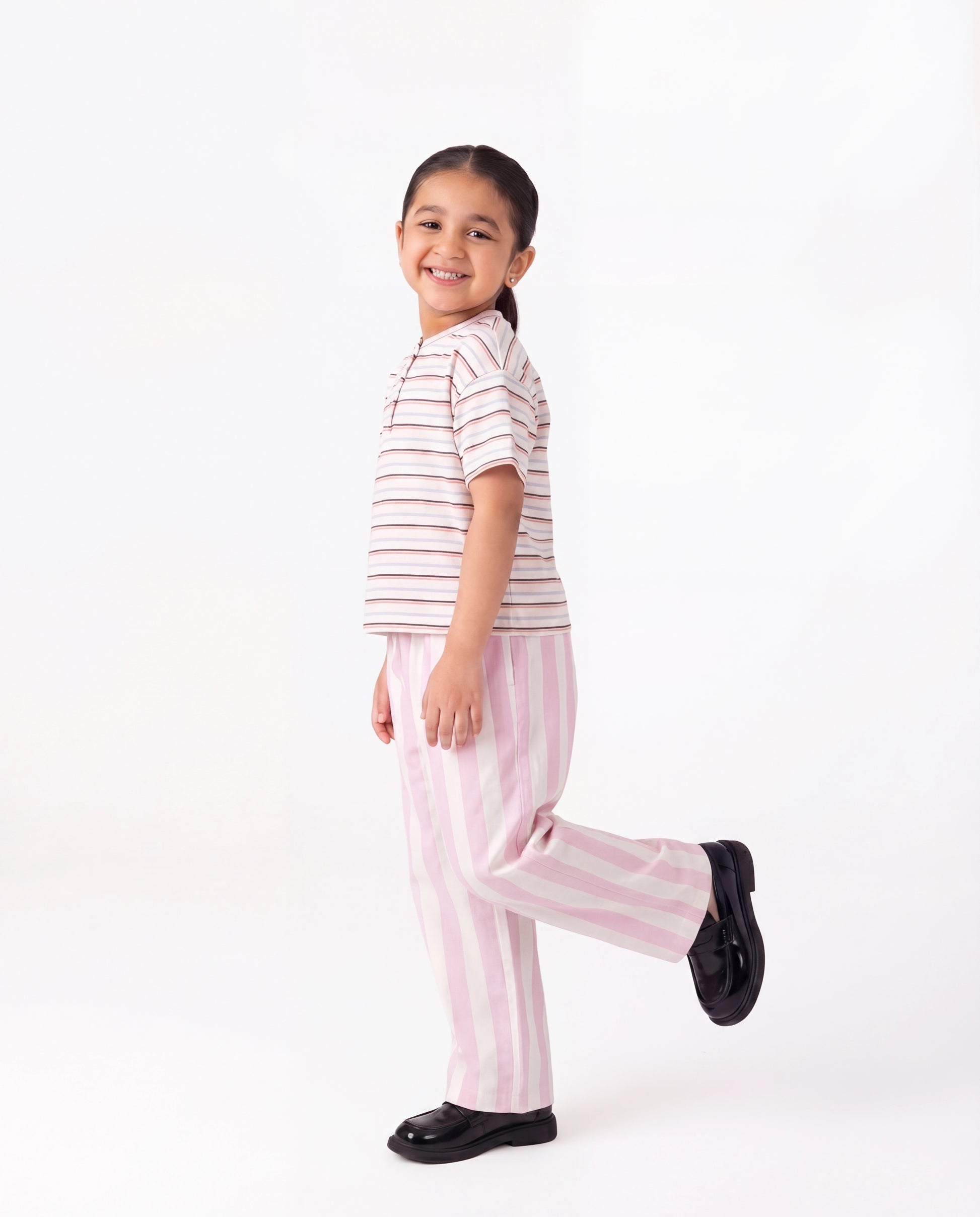 Child wearing pink and white striped pajamas on a white background