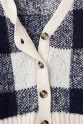 Close-up of PTex Fashion navy and ecru check knit cardigan showing ribbed button band, buttonhole and tortoiseshell-effect buttons