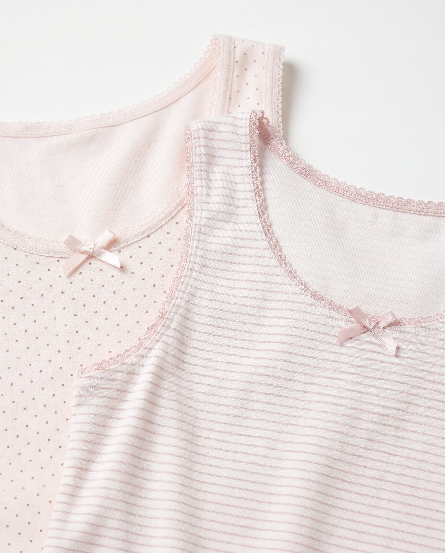 close look image of Girls white and pink pinstripe and polka dot sleeveless cotton tank top with pink lace trim neckline, armhole edging and satin bow, flat lay product photo