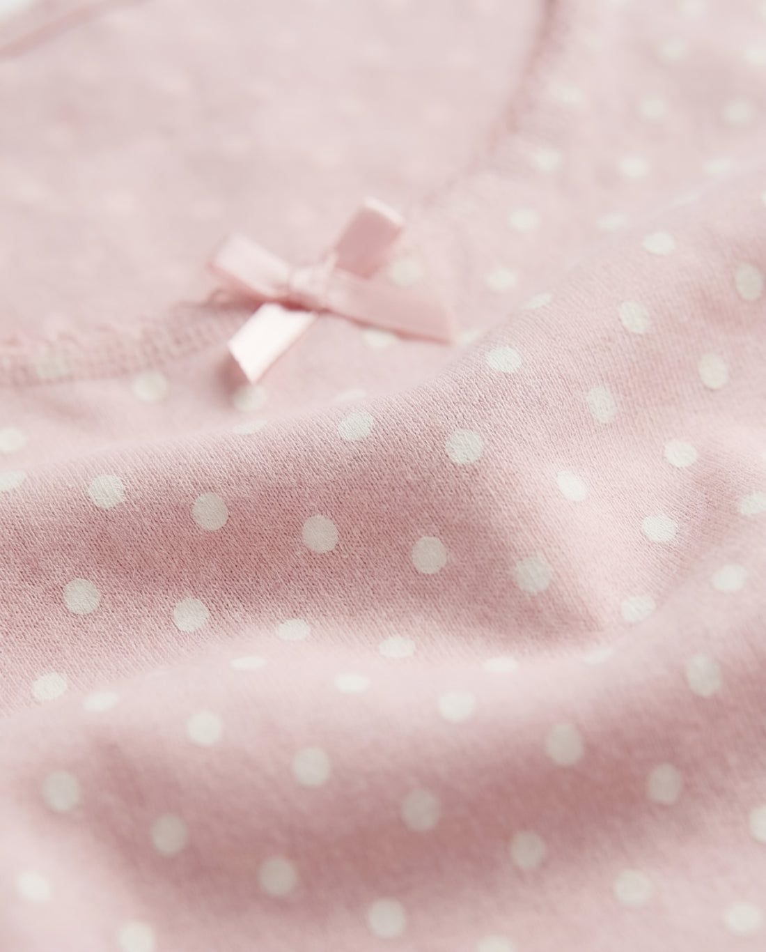 Girls pink polka dot sleeveless tank top with lace trim neckline and satin bow, flat lay product photo