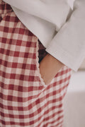 On-model pocket detail: PTex Fashion girls' berry gingham cotton trousers, hand in scalloped trim side pocket