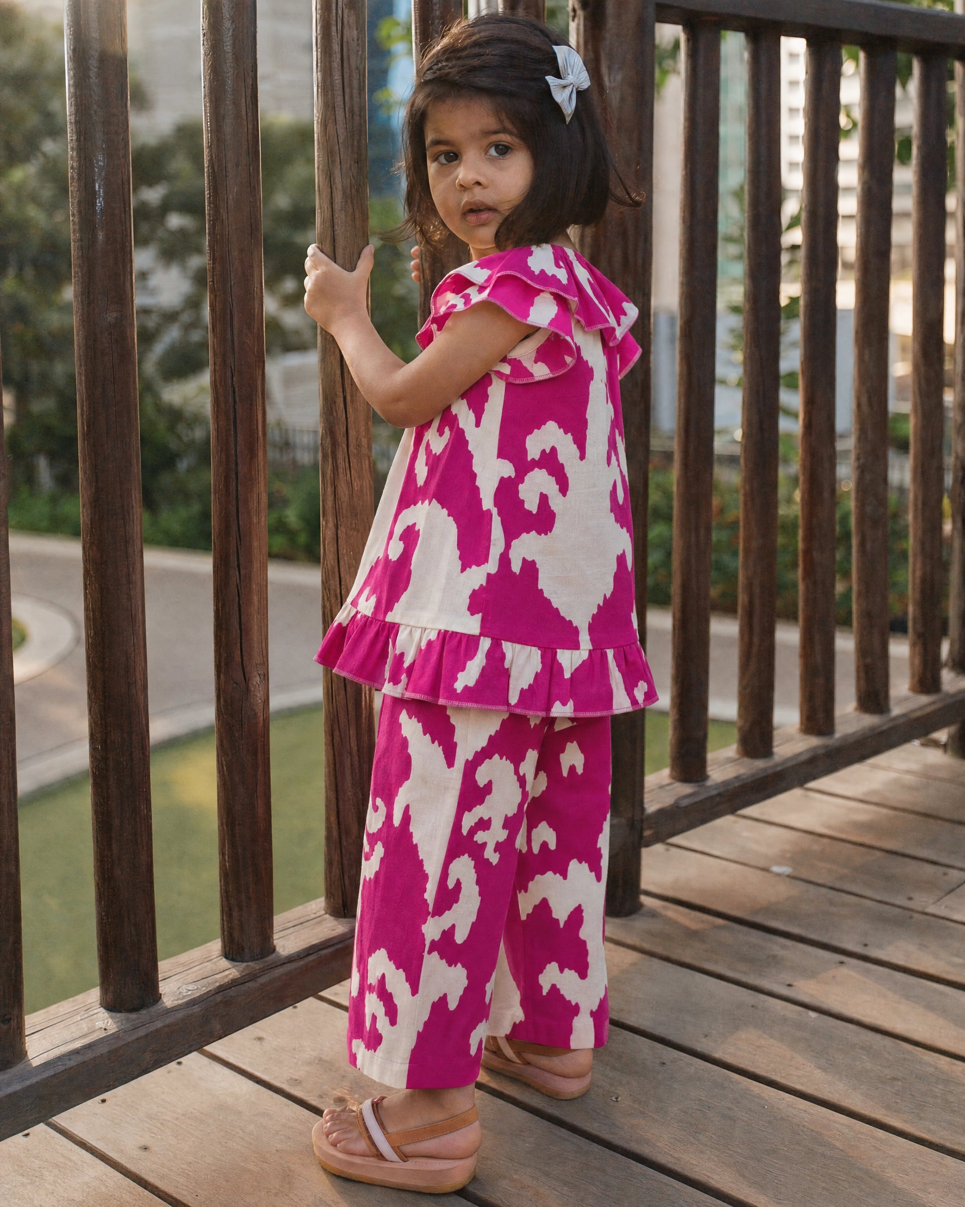 Girl wearing PTex Fashion magenta ikat print linen co-ord set with ruffle top and wide-leg pants, back view outdoors