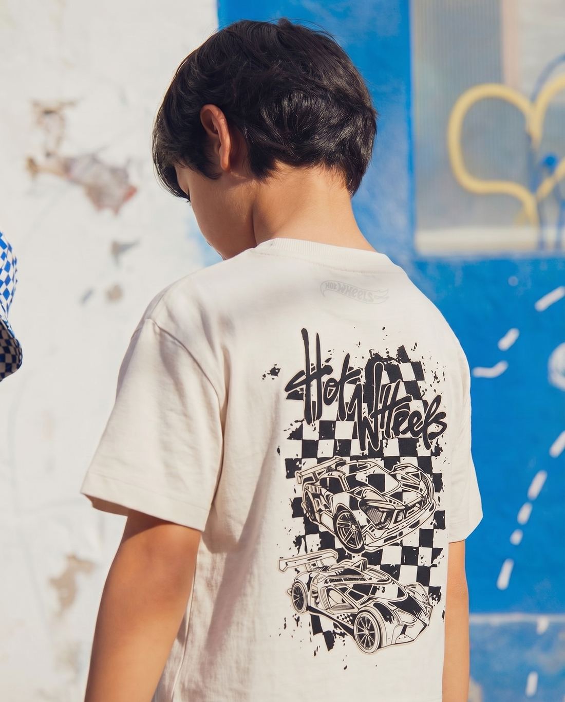  Front flat lay: Front view flat lay of an off-white toddler drop shoulder tee with a vertical stacked "Full Throttle / Hot Wheels" graphic featuring three race cars in black and ice blue on the left chest panel.