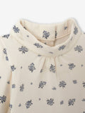 Close-up of a cream-colored blouse with blue floral patterns on a white background