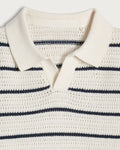 Close-up of a white knit sweater with navy stripes on a light gray background