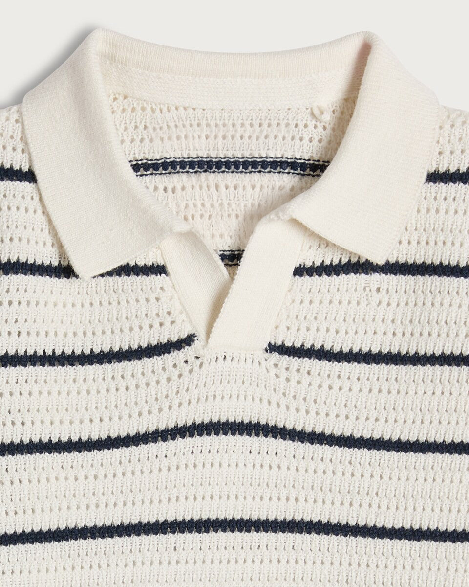 Close-up of a white knit sweater with navy stripes on a light gray background
