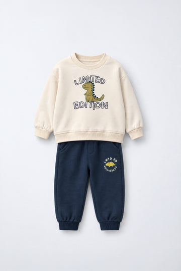 PTex Fashion kids’ two-piece set with a cream crew-neck sweatshirt featuring a dinosaur graphic and navy joggers with ribbed ankle cuffs, flat lay