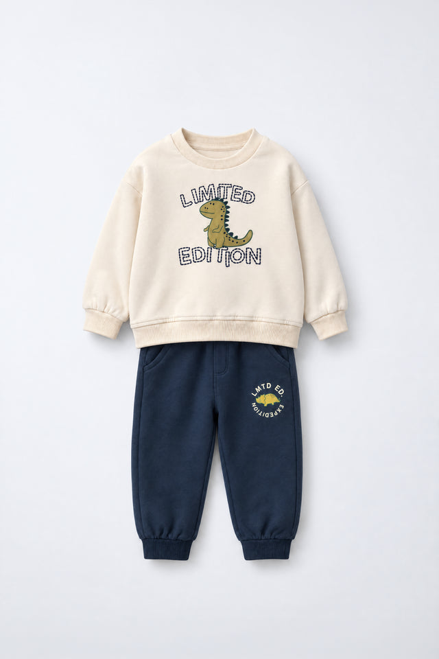 PTex Fashion kids’ two-piece set with a cream crew-neck sweatshirt featuring a dinosaur graphic and navy joggers with ribbed ankle cuffs, flat lay