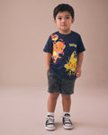 Child wearing a navy blue t-shirt with cartoon characters on a beige background