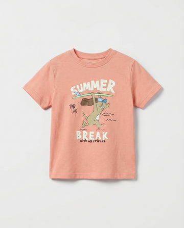kid's salmon pink short sleeve cotton t-shirt with cartoon surfing animal, beach scene, and "Summer Break with my friends" graphic print on front, flat lay on light grey background