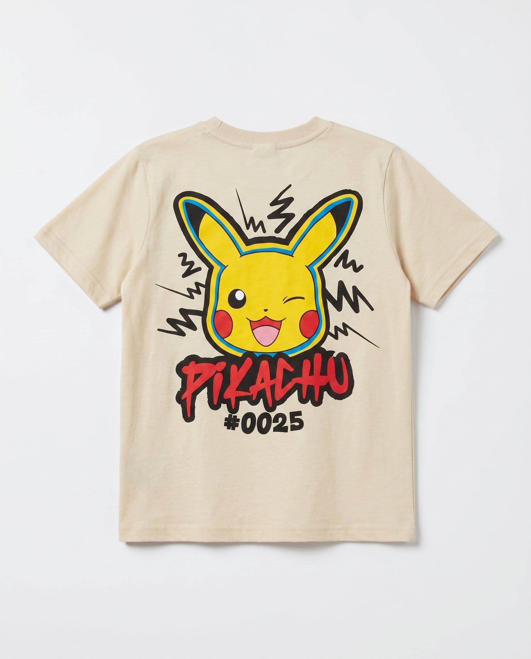 Flat lay showing the back of a cream boys' t-shirt with a large Pikachu street-art style graphic, zigzag electric bolt lines, and graffiti text