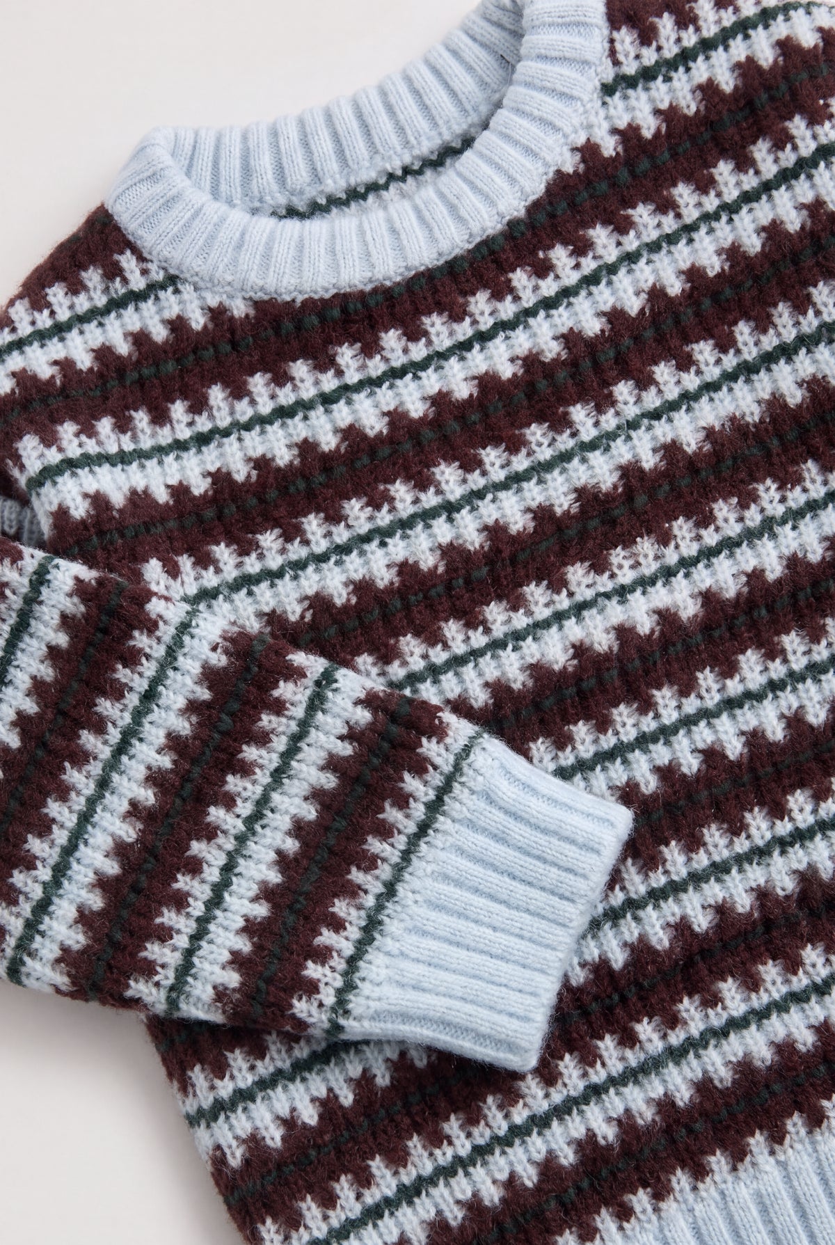 Close-up of the PTex Fashion kids’ ice blue and burgundy jacquard knit sweater showing the ribbed crew neck and cuff