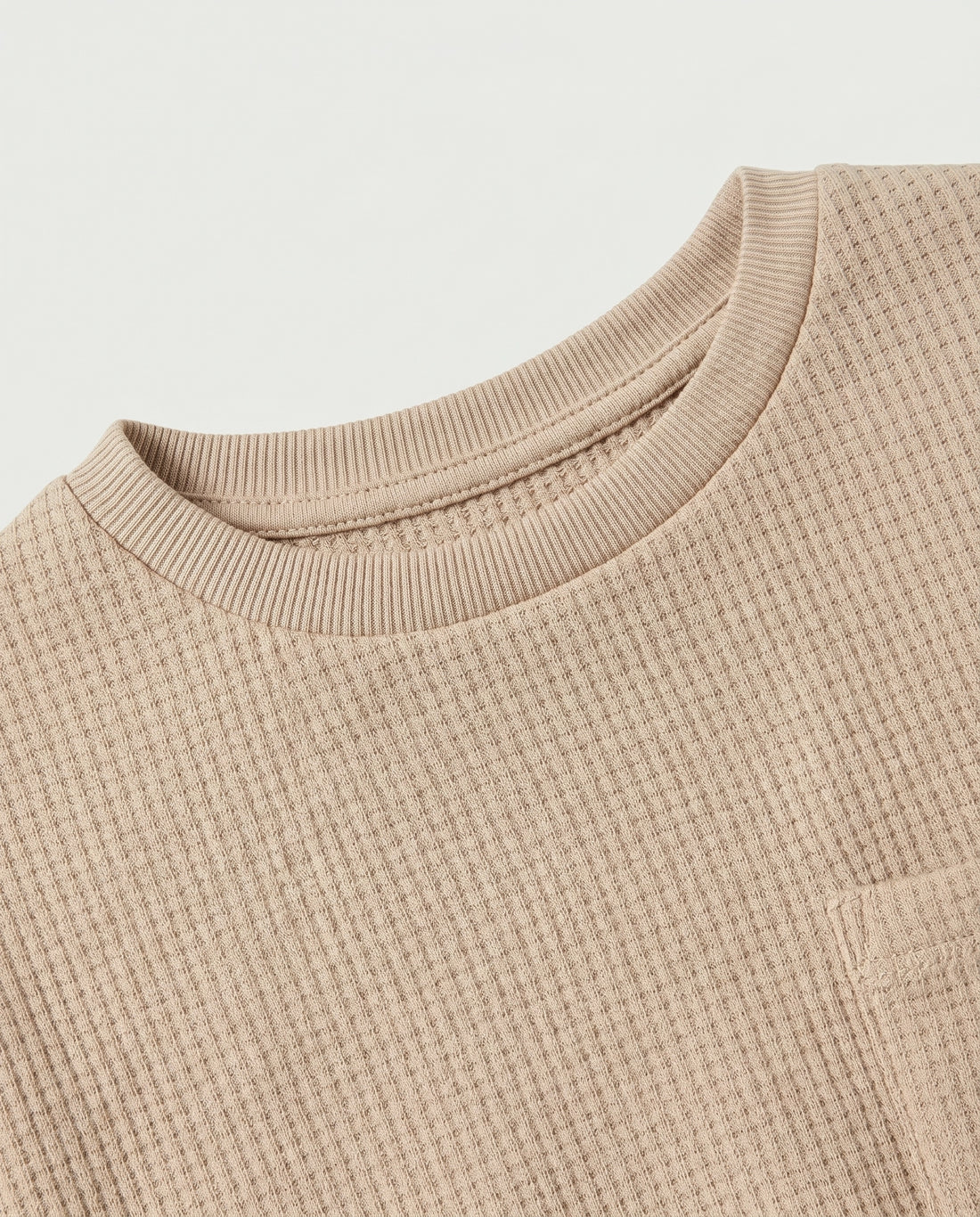 Full flat lay front view:
Kids' drop shoulder waffle cotton t-shirt in sand displayed flat lay on a white background, showing a relaxed boxy silhouette, ribbed crew neckline, short sleeves with ribbed cuffs, tonal chest patch pocket, and finished base hem.
