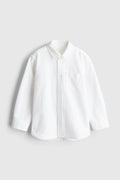 White toddler boys shirt on a light gray background