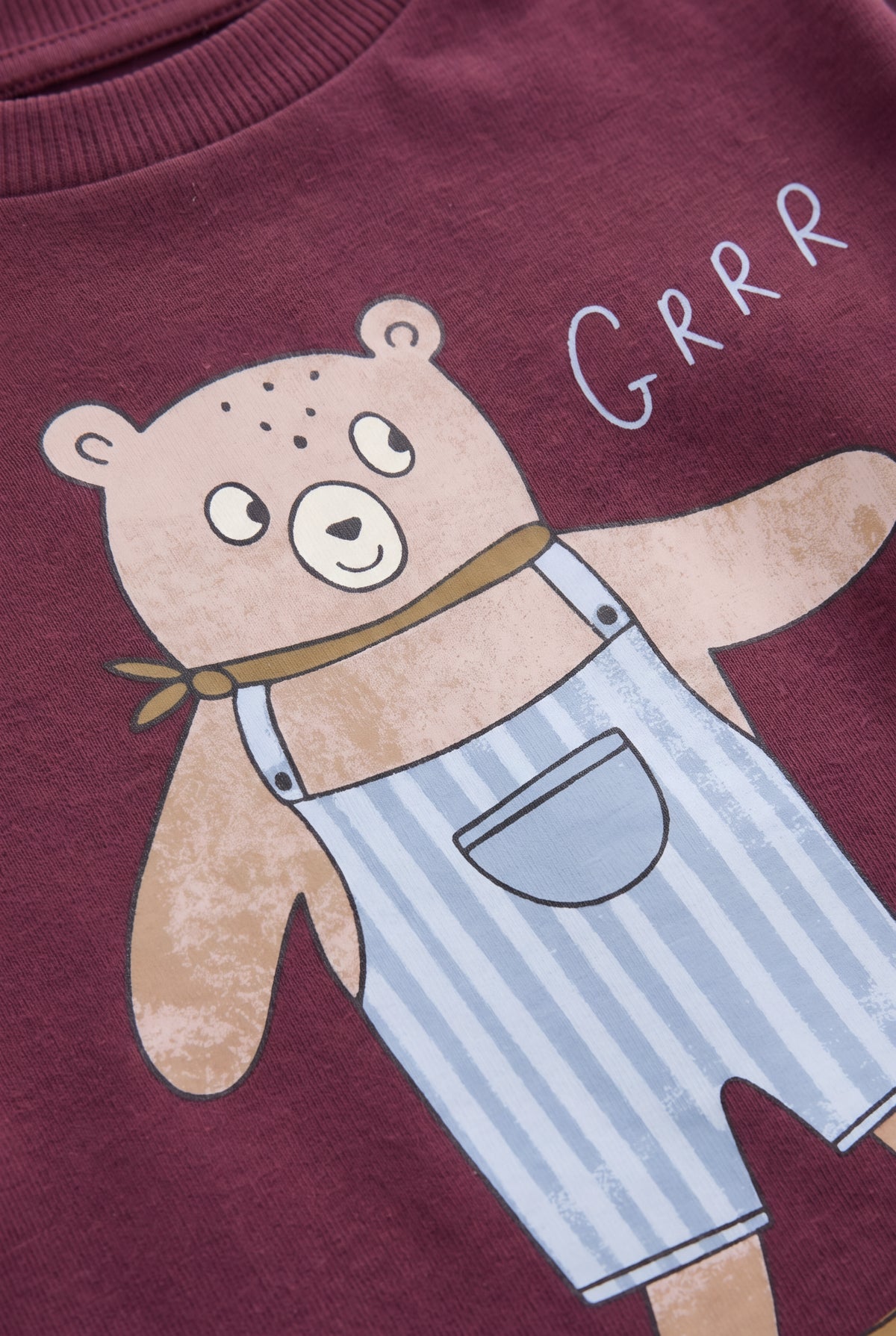 PTex Fashion close-up of the bear in striped dungarees print and ribbed collar on a burgundy t-shirt