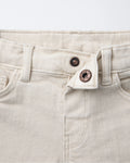 Close-up of toddler denim Bermuda shorts showing adjustable copper snap-button waistband closure and belt loops in off-white ecru wash.