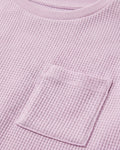close up image of Toddler girls' waffle-knit cotton t-shirt in pink lilac with a ribbed crew neck, short sleeves, and a chest patch pocket, laid flat on a light grey background.
