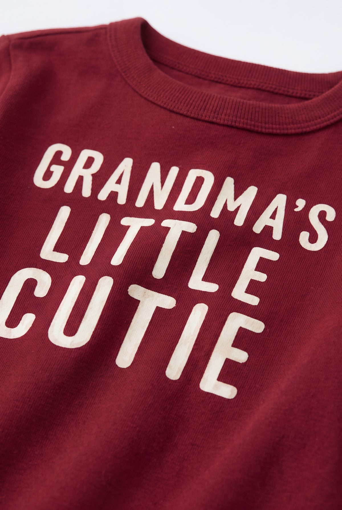 PTex Fashion baby tshirt close-up showing ribbed crew neck and cream Grandma’s Little Cutie lettering