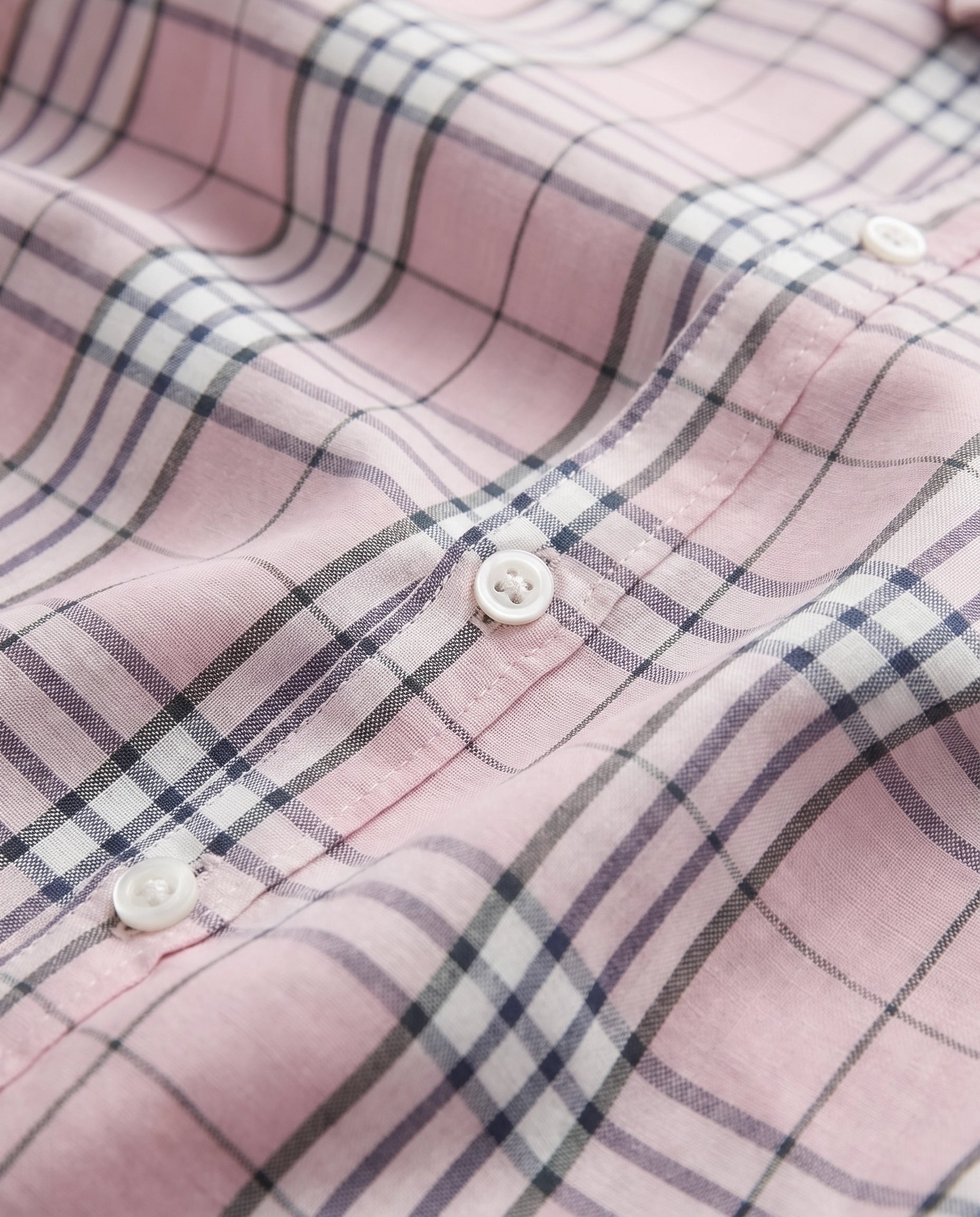 Close-up of pink check fabric and white buttons on a PTex Fashion boys' cotton shirt