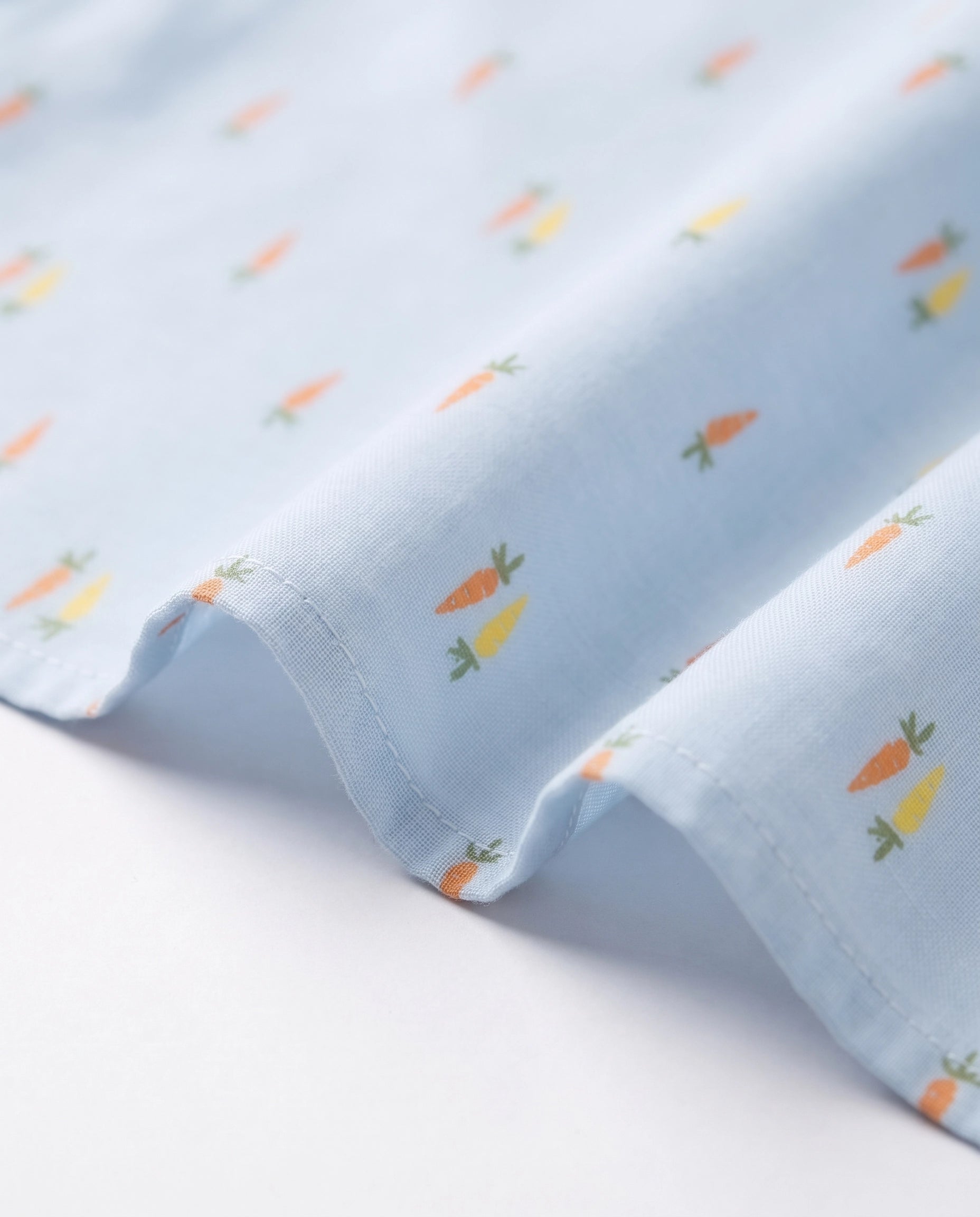 Fabric close-up of a PTex Fashion cotton shirt with orange and yellow carrot print