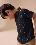 Child wearing a navy blue shirt with chili pepper pattern on a beige background